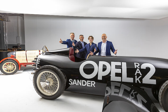 Abbildung des Fahrzeugs Opel RAK 2 mit 4 Personen die hinter dem Wagen stehen.