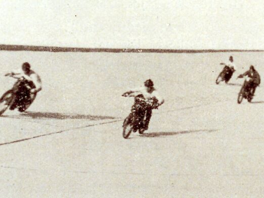 Schwarz-weiß Aufnahme von mehreren Motorradfahrern auf der Rennstrecke.