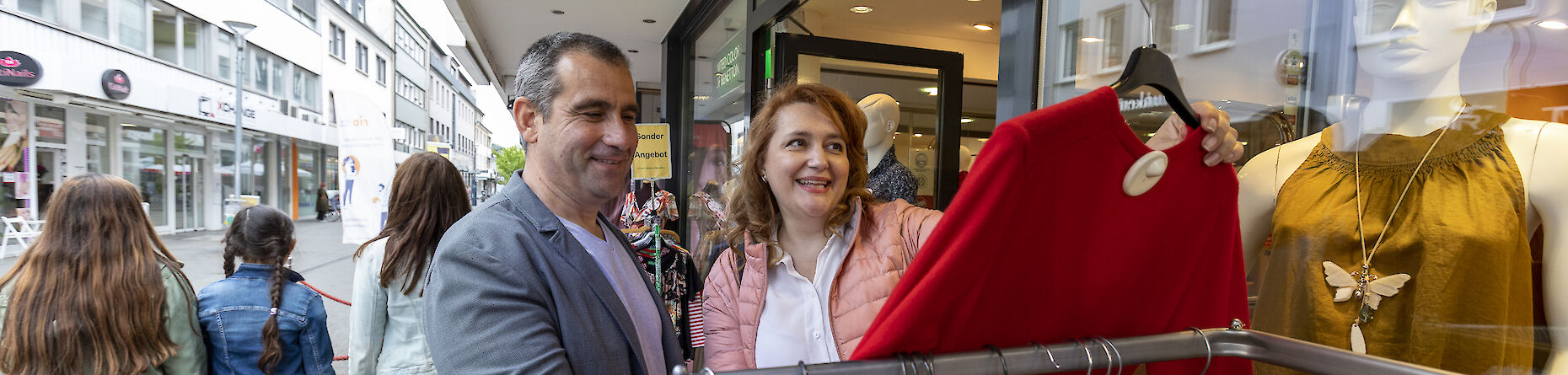 Eine Frau und ein Mann beim Einkaufen. Die Frau hält einen roten Pullover in der Hand.