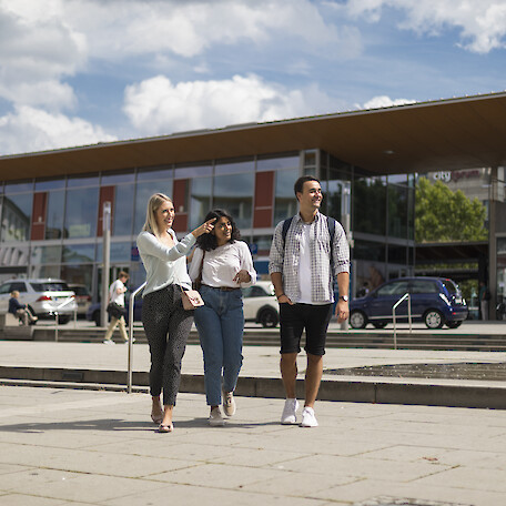 Drei junge Leute stehen vor dem Bahnhofsgebäude