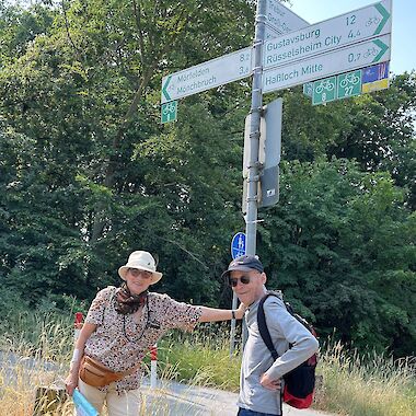 Wilma und Bengt beim Start ihrer Tour in Alt-Haßloch vor einem Schild, das die verschiedenen Richtungen zeigt.
