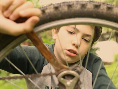 Ein Junge repariert sein Fahrrad.