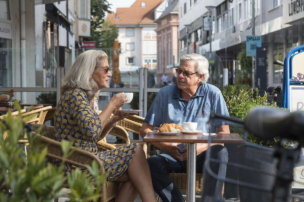 Eine Frau und ein Mann trinken eine Kaffee in der Fußgänger-Zone.