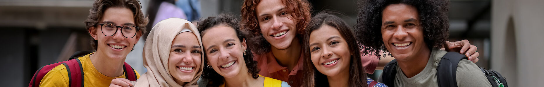 Eine multikulturelle Gruppe von Jugendlichen, die lächelnd in die Kamera schauen.