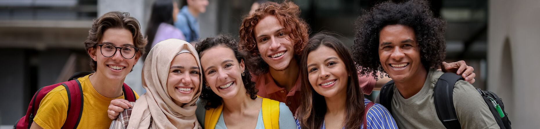 Eine multikulturelle Gruppe von Jugendlichen, die lächelnd in die Kamera schauen.