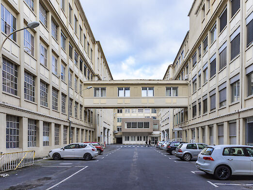 Adamshof im Opel-Altwerk: rechts und links die Häuserfassaden und parkende Autos davor.