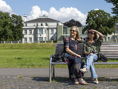 2 Frauen auf einer Bank vor den Opelvillen.