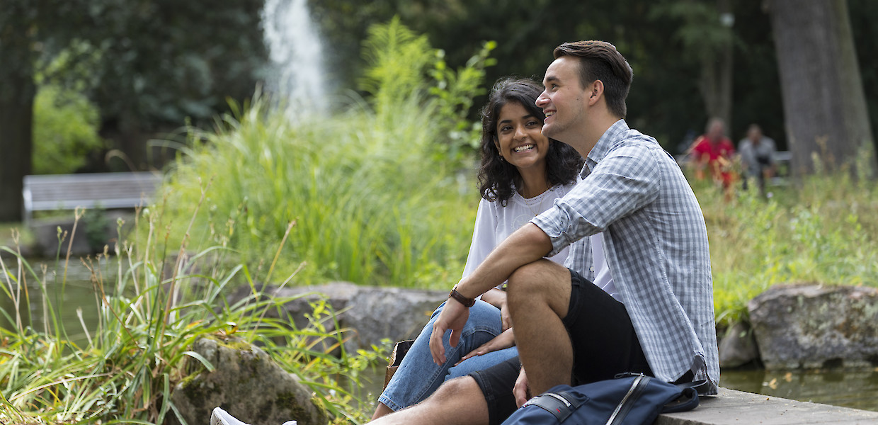 Ein junges Paar sitzt am Teich