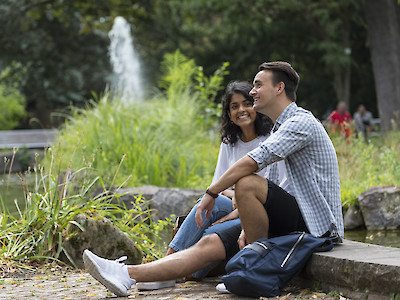 Ein junges Paar sitzt am Teich